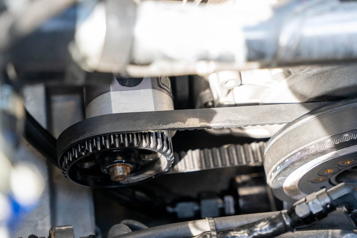 Worn timing belt on a pulley and tensioner in a car engine at 1st Wheels Garage