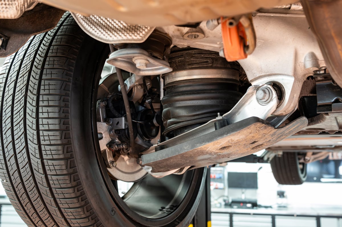 Car raised on a lift showing the suspension and shock absorber at 1st Wheels Garage