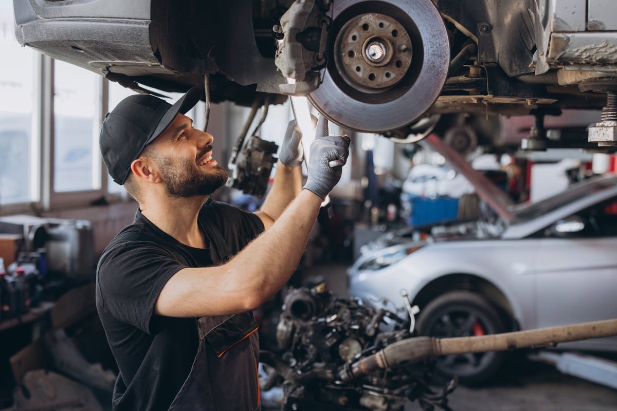 Mechanic inspecting a car exhaust and braking components on a lift at 1st Wheels Garage